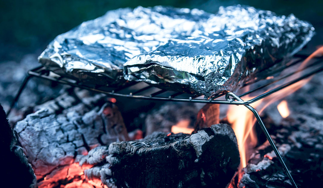 Papillotes d'aluminium sur la flamme d'un Bbq